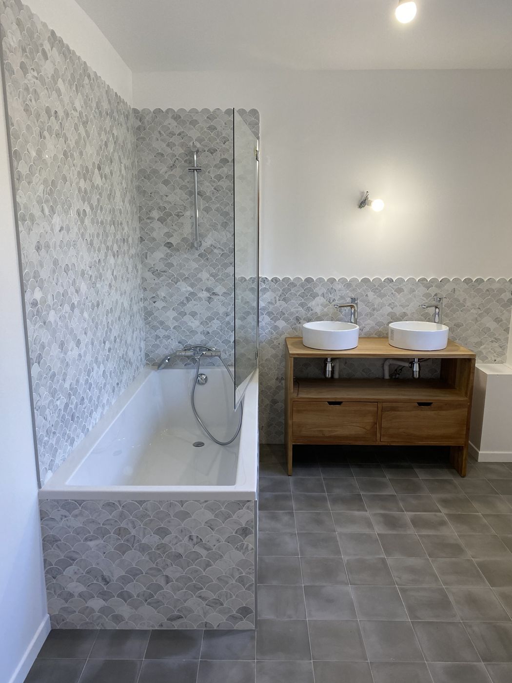 Salle de bain en mosaïque d'écailles de marbre, baignoire et double vasque en teck