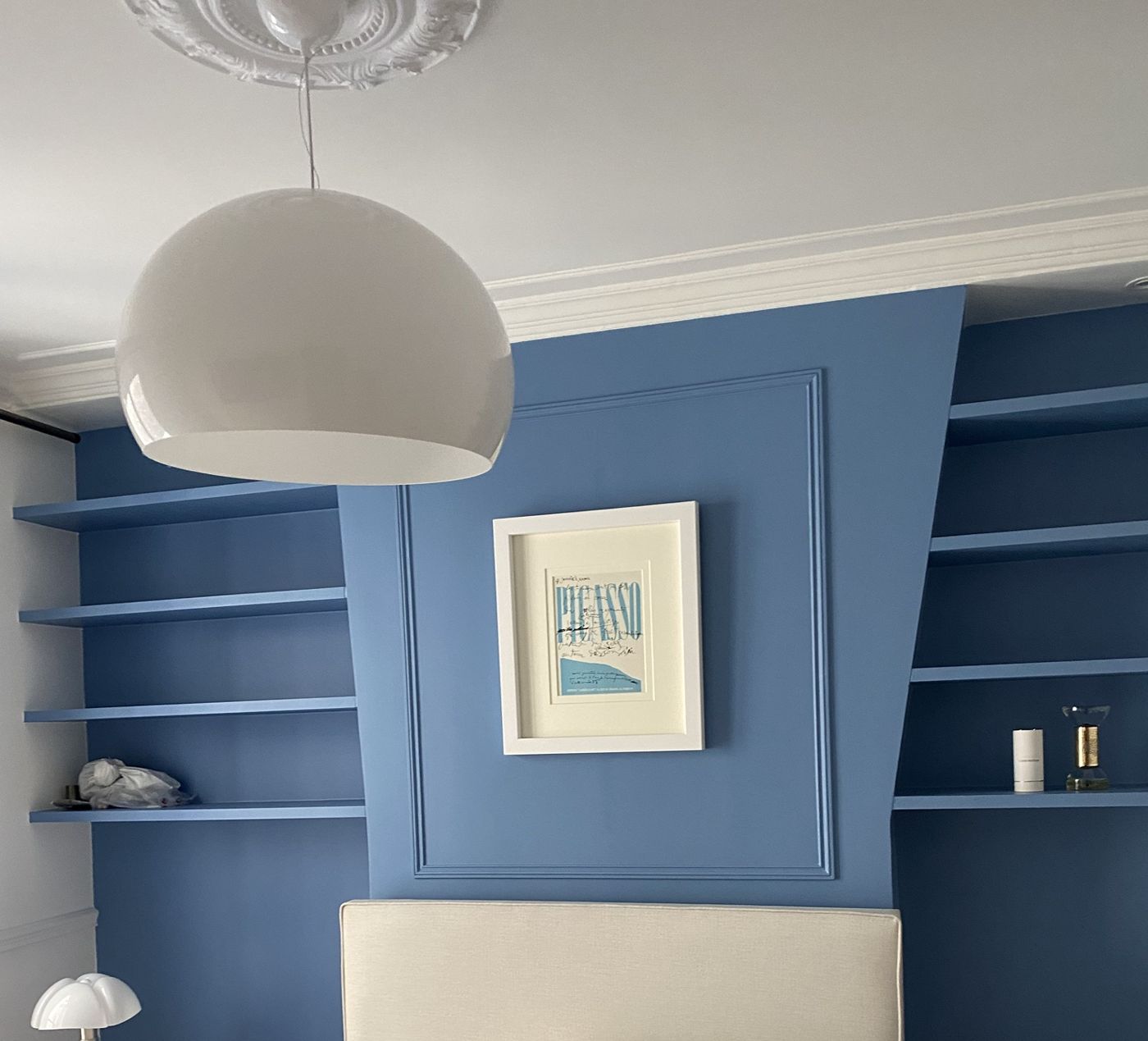 Chambre bleue avec étagères sur mesure et moulure encadrant la tête de lit