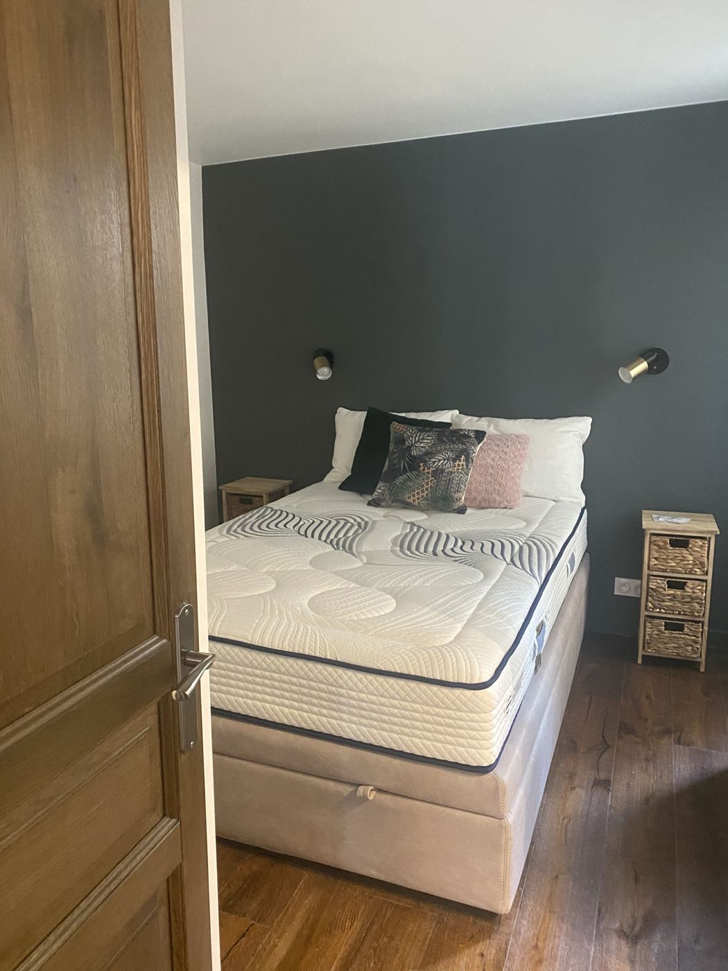 Chambre avec mur gris anthracite, appliques en laiton et parquet foncé
