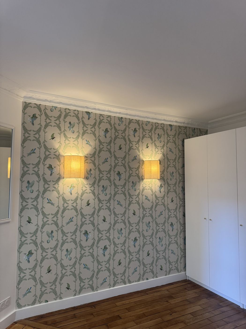 Chambre avec papier peint vert à oiseaux et deux appliques en lin