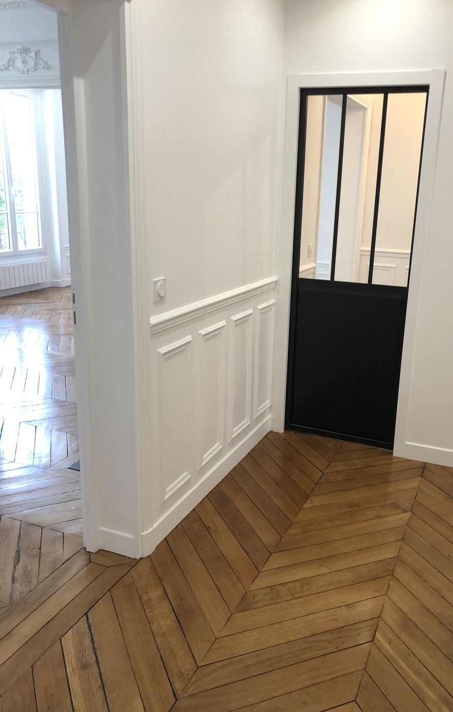 Couloir avec lambris, porte vitrée style atelier et parquet à chevrons