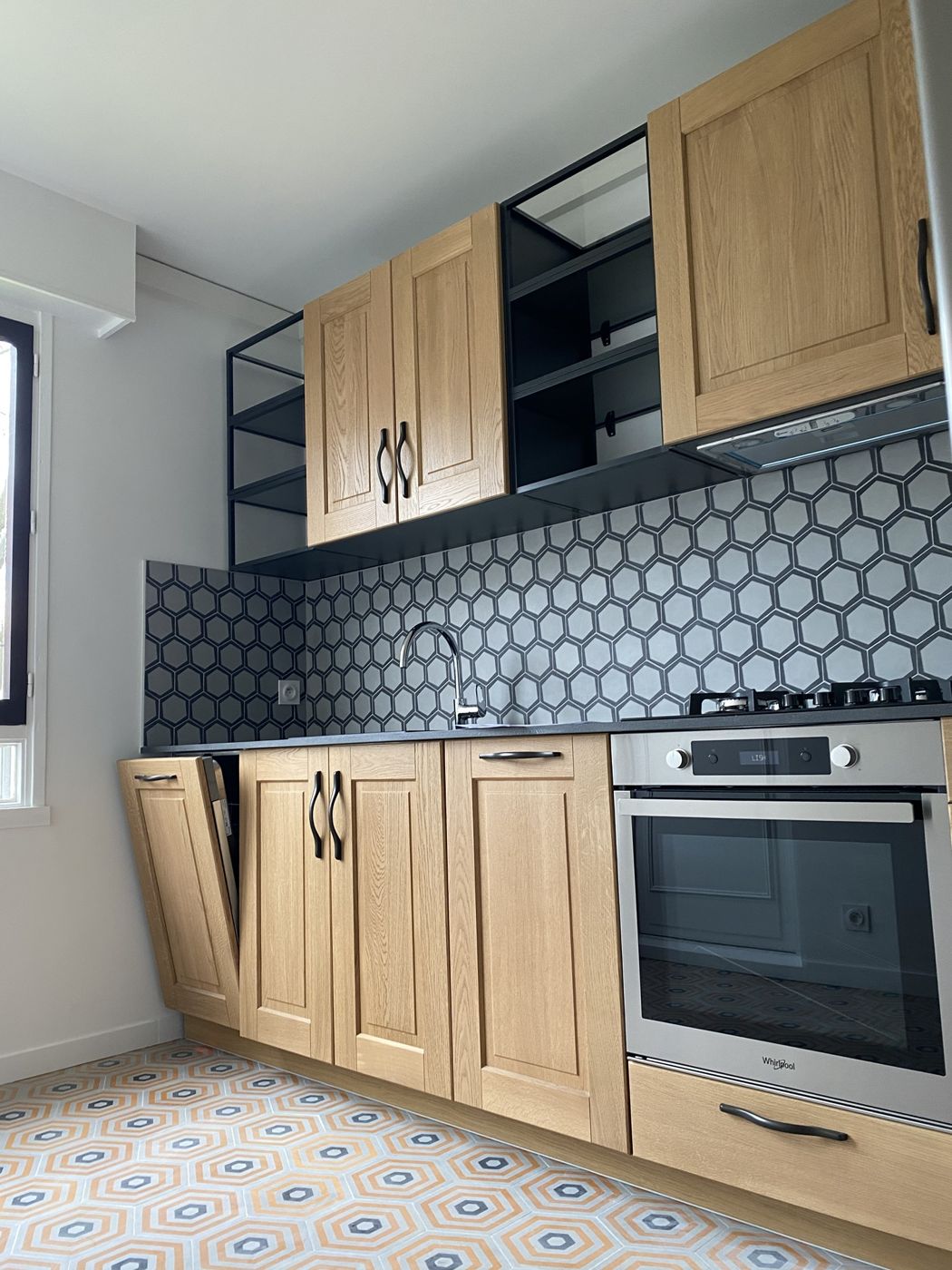 Cuisine en chêne avec crédence hexagonale, étagères métalliques noires et sol en carreaux orange