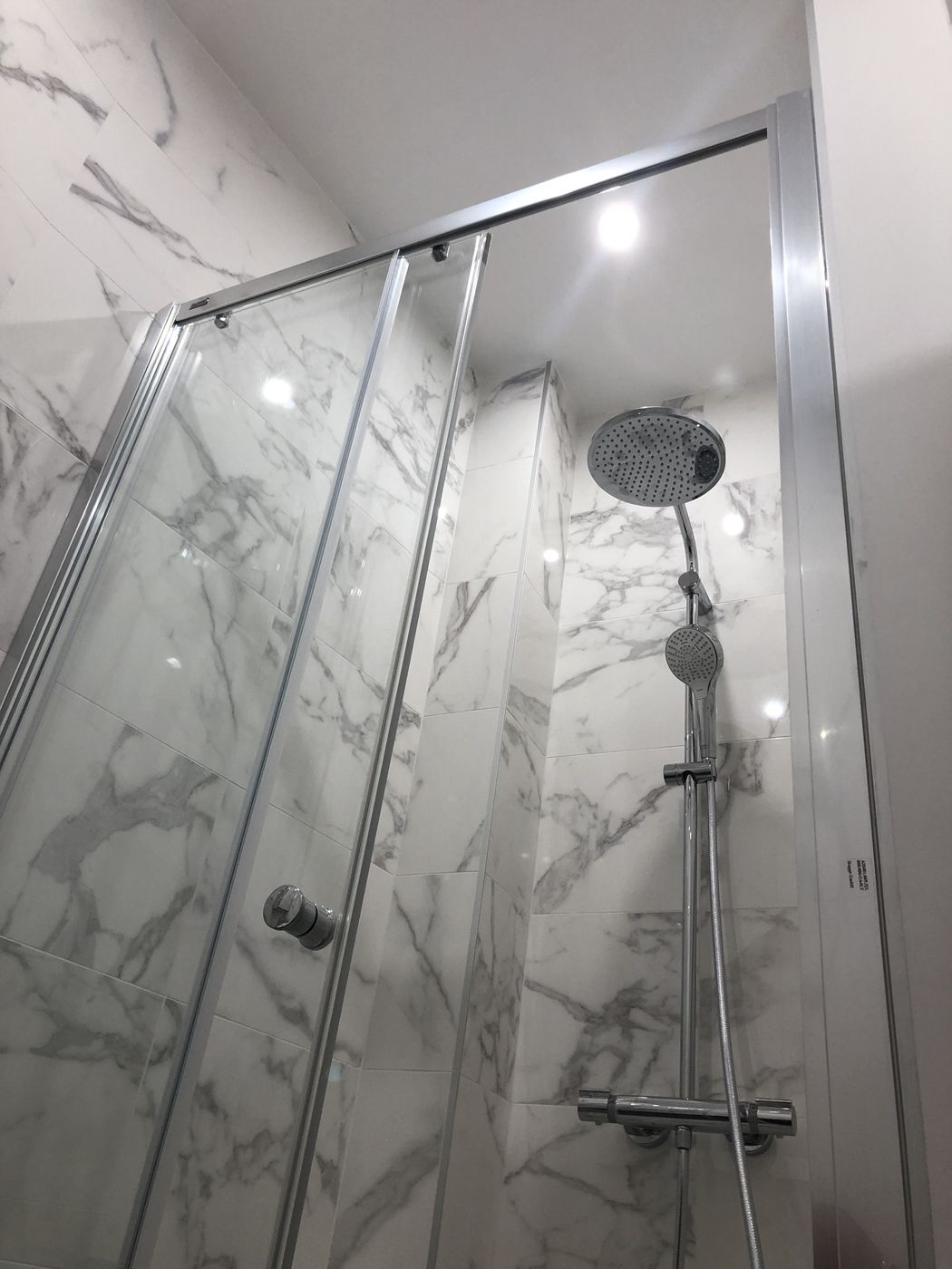 Douche à l'italienne en carrelage effet marbre avec colonne de douche
