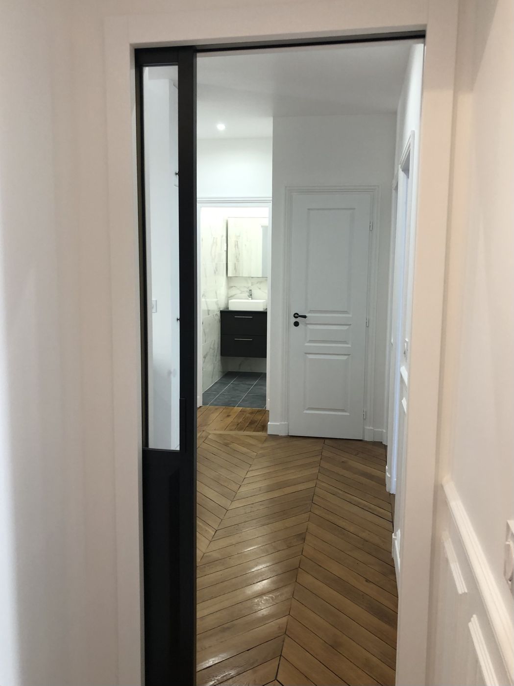Porte coulissante vitrée noire donnant sur le couloir