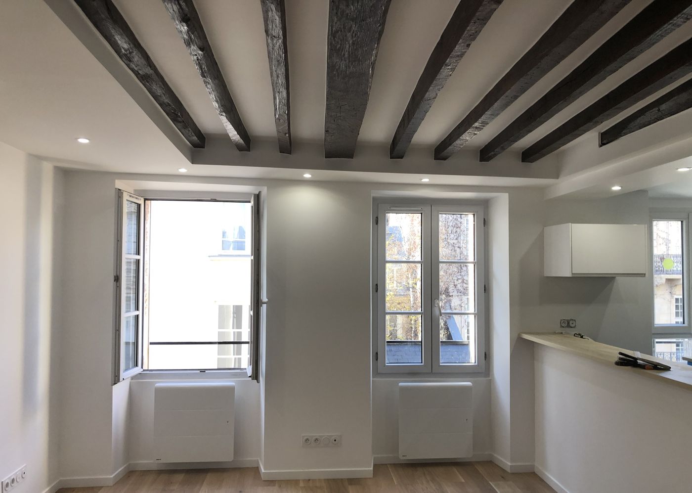 Séjour avec poutres apparentes, spots encastrés et parquet clair