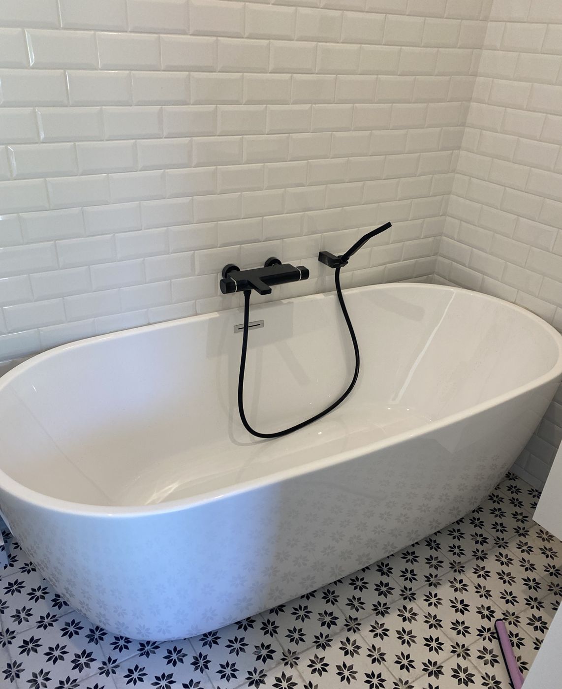 Baignoire îlot avec robinetterie noire, faïence métro blanche et carreaux de ciment