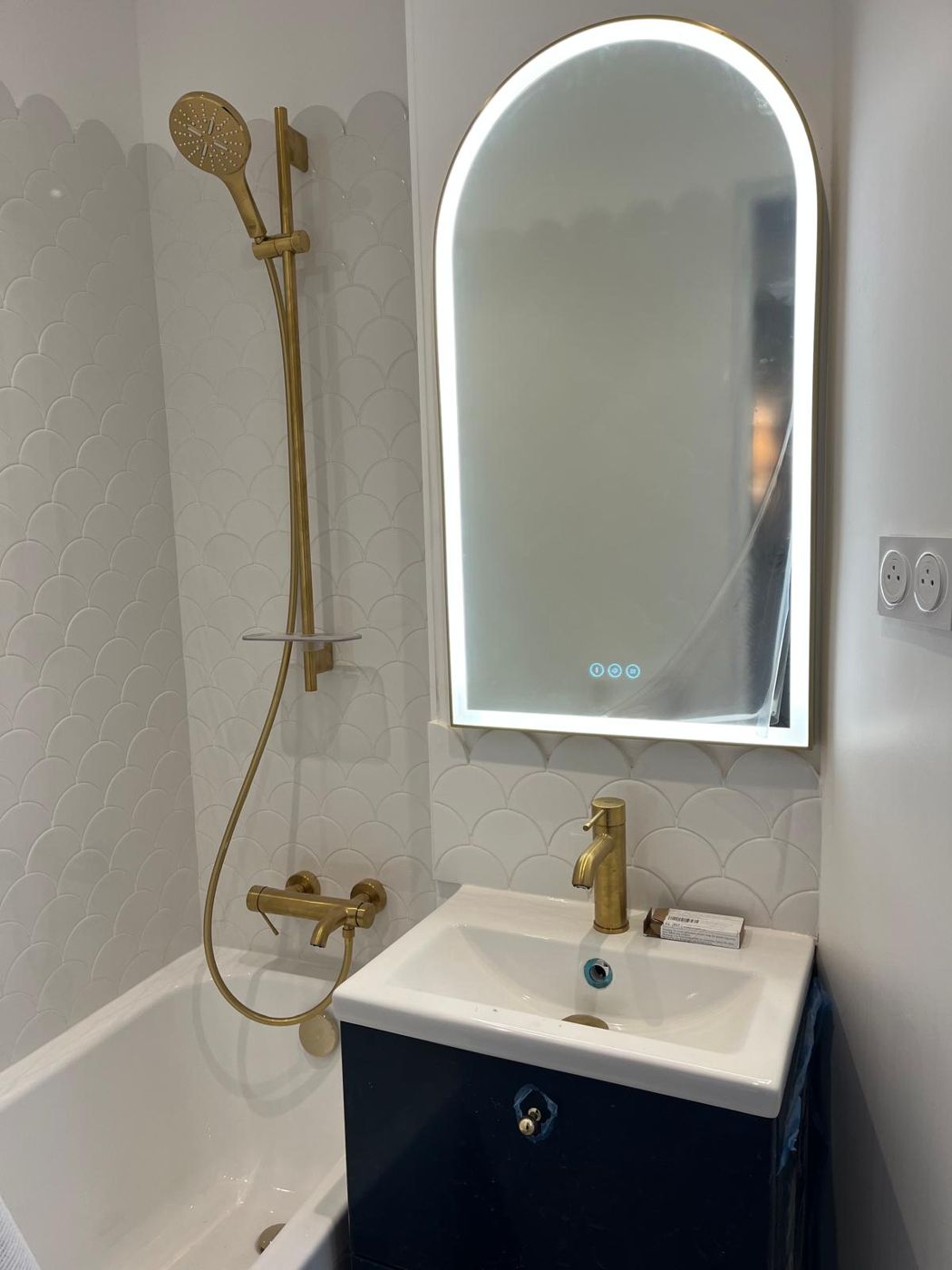 Salle de bain avec robinetterie en laiton brossé et miroir arqué lumineux