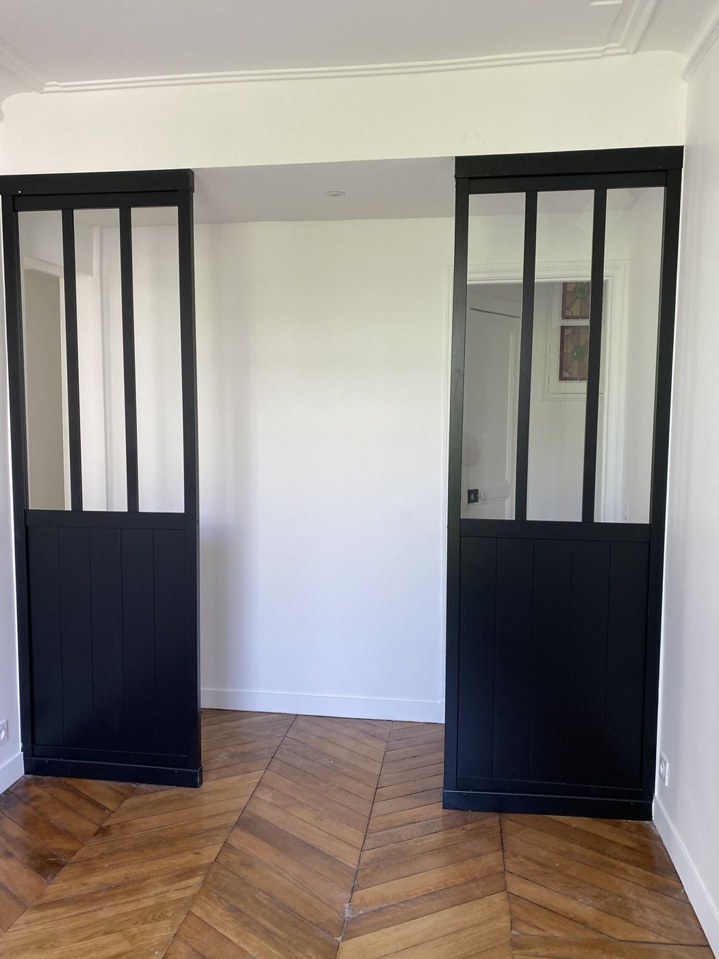 Deux cloisons vitrées style verrière noire sur parquet à chevrons